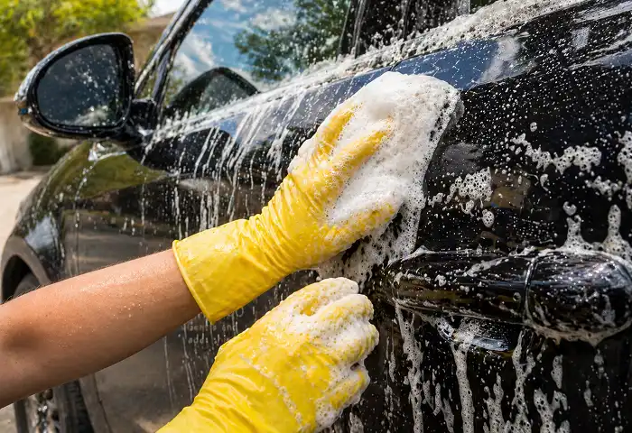 applying homemade foam car shampoo on black car door