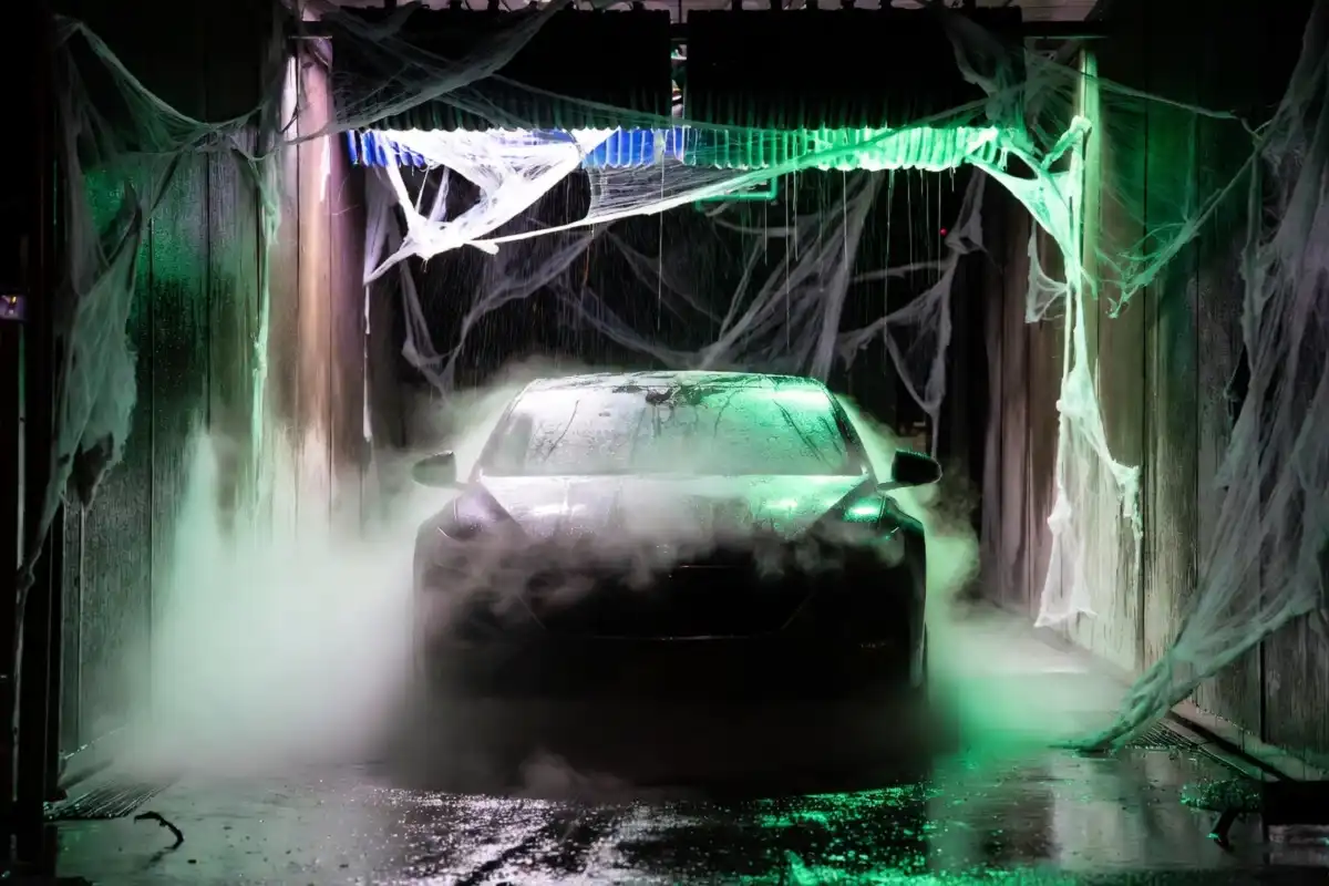 Car going through a spooky Halloween-themed automated car wash with colored lighting and fog