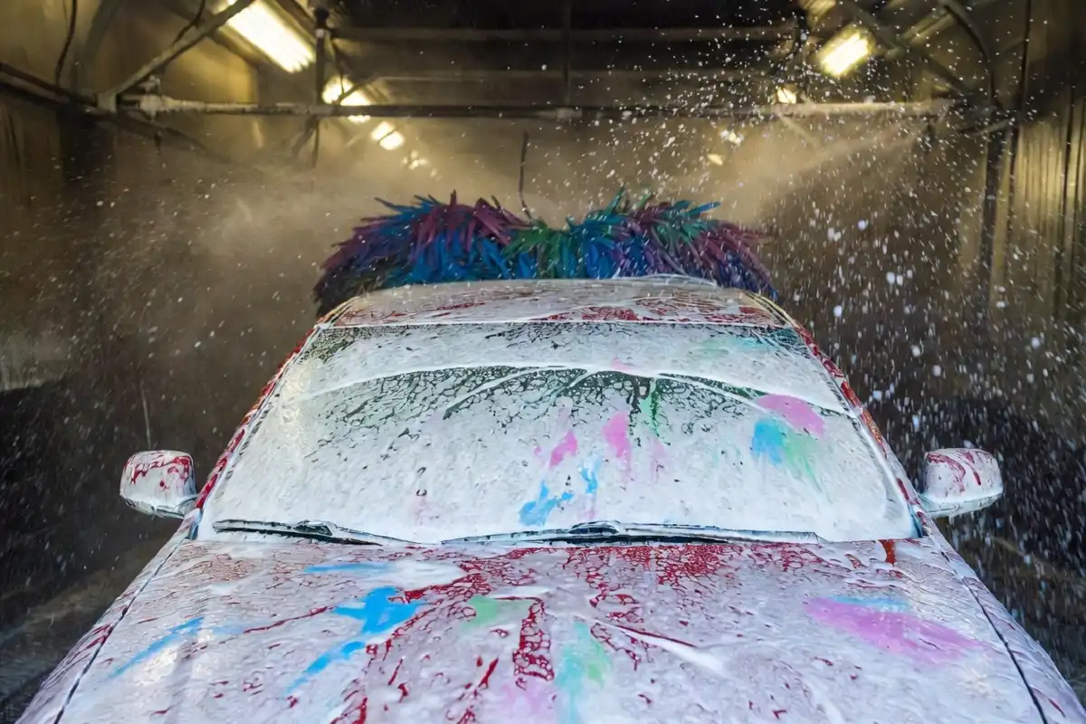 High-pressure foam and water jets cleaning a car in an automatic splash car wash