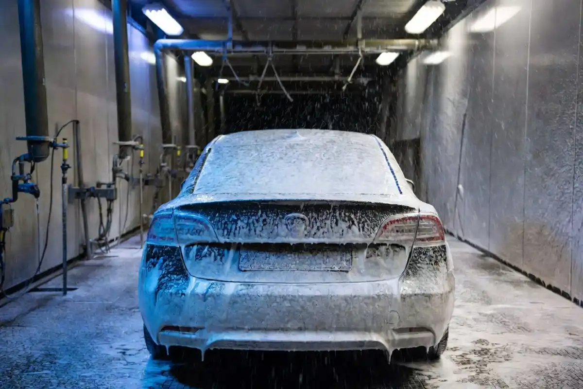 A car moving through a professional best car wash tunnel with blue foam and bright lighting