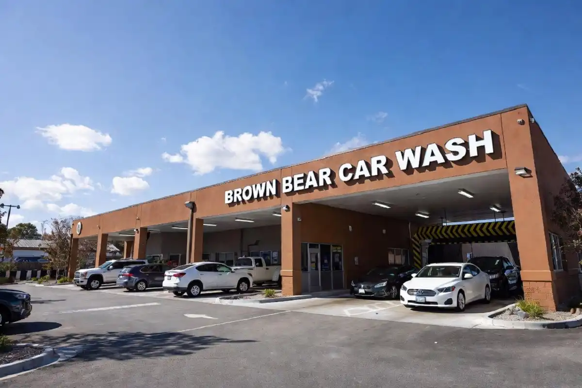 Brown Bear Car Wash exterior location with vehicles lined up at the entrance on a sunny day