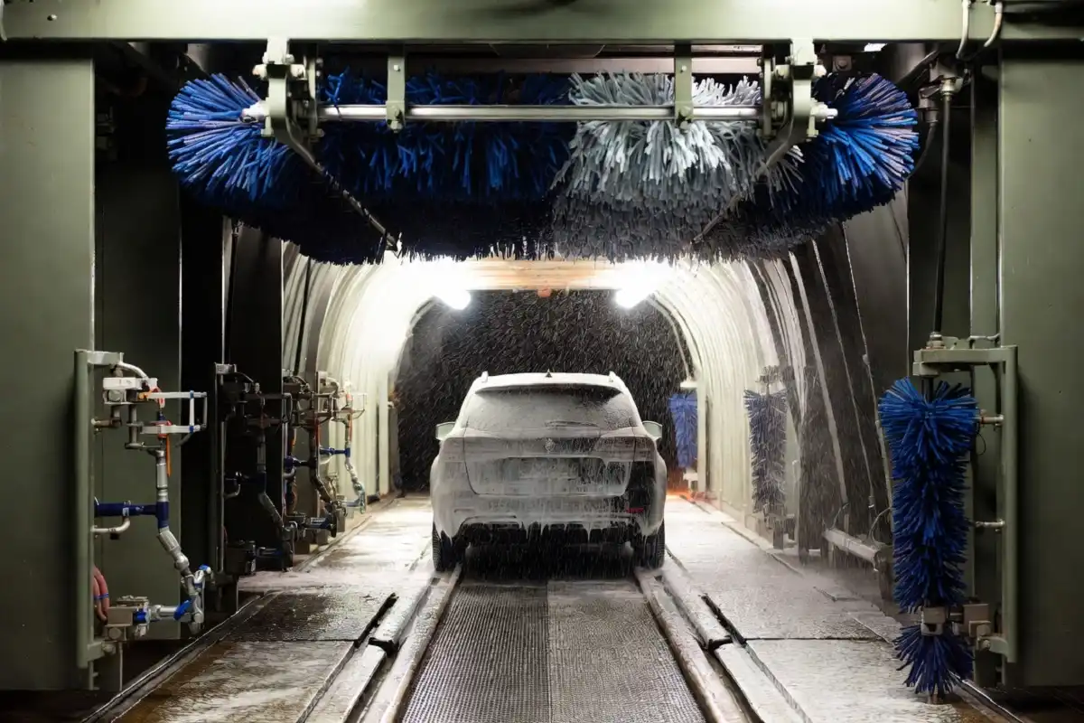 Automated tunnel wash process inside a Brown Bear Car Wash with foam and brushes cleaning a vehicle