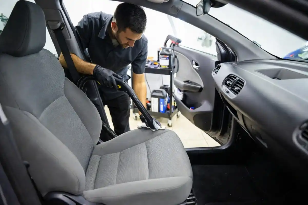 A professional detailer cleaning the interior of a car at a detailing station