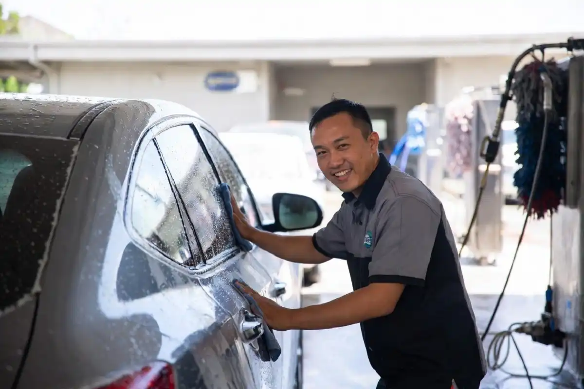 A car wash jobs cleaning the exterior of a vehicle at a professional car wash facility