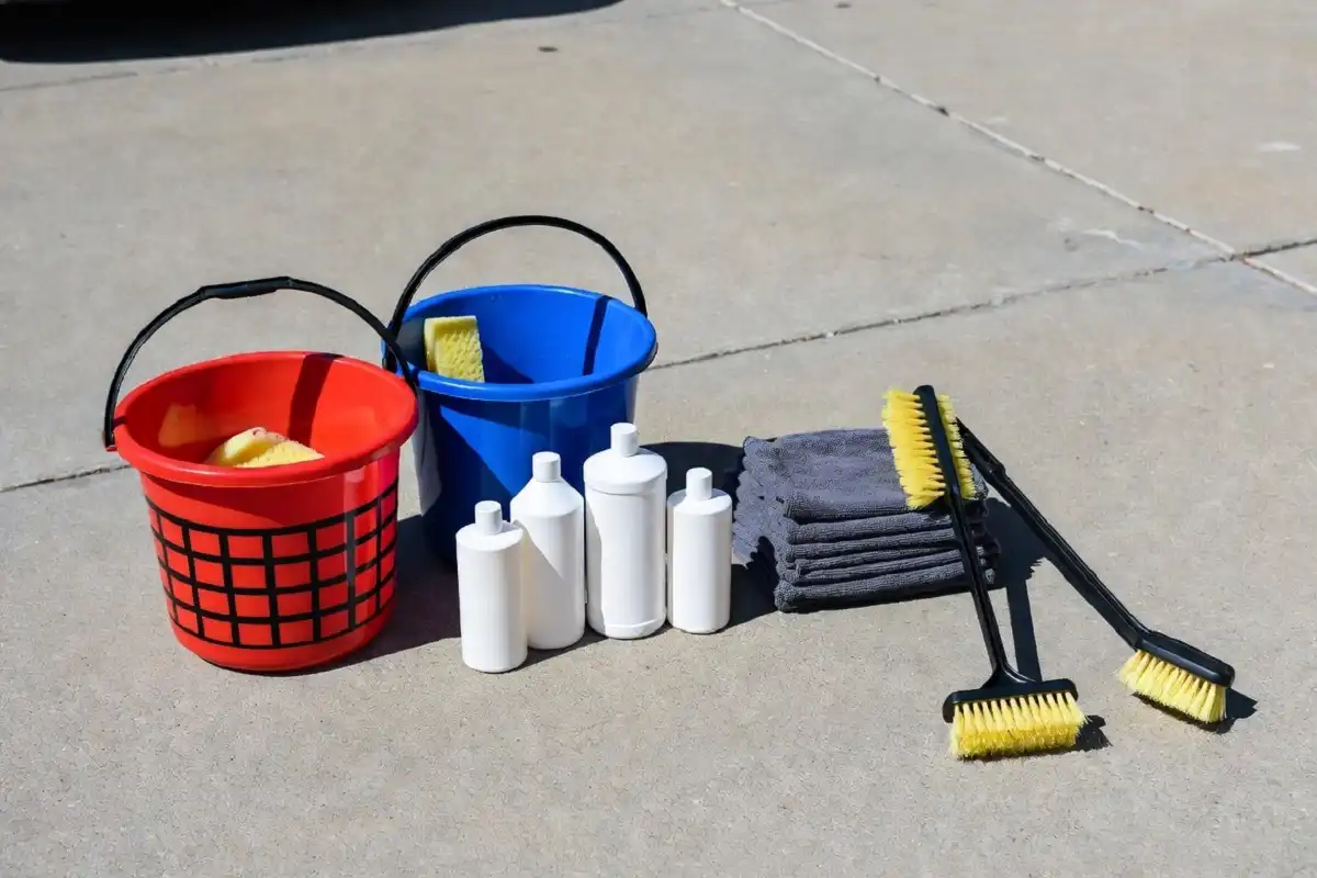 A complete car wash kit laid out on a driveway including buckets, mitts, and soap