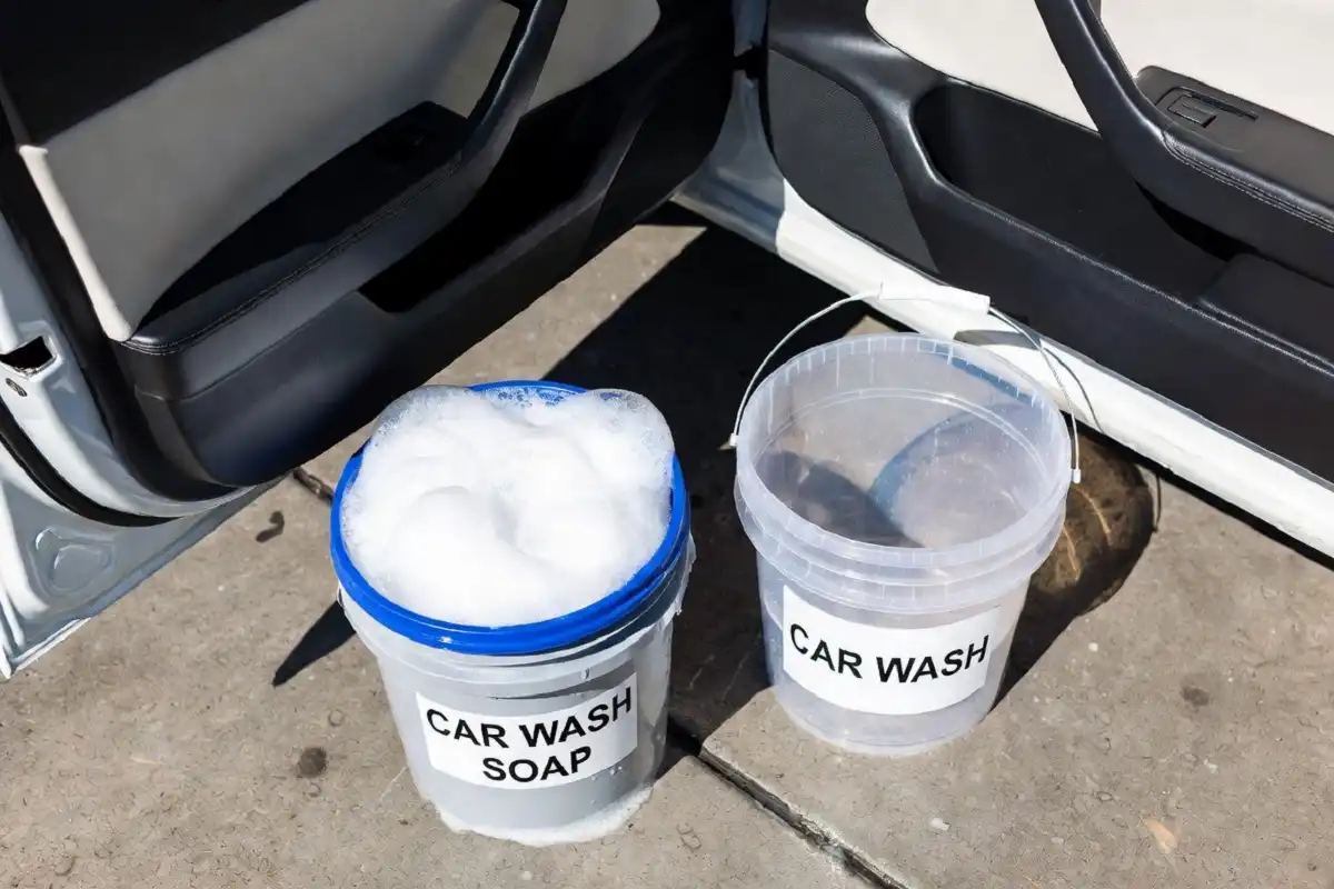 Two buckets of water set up for the two-bucket car washing method on a driveway