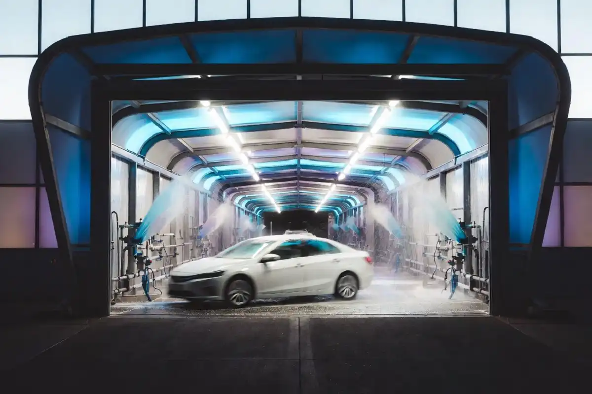 Car entering a drive through car wash tunnel with colorful foam and lights