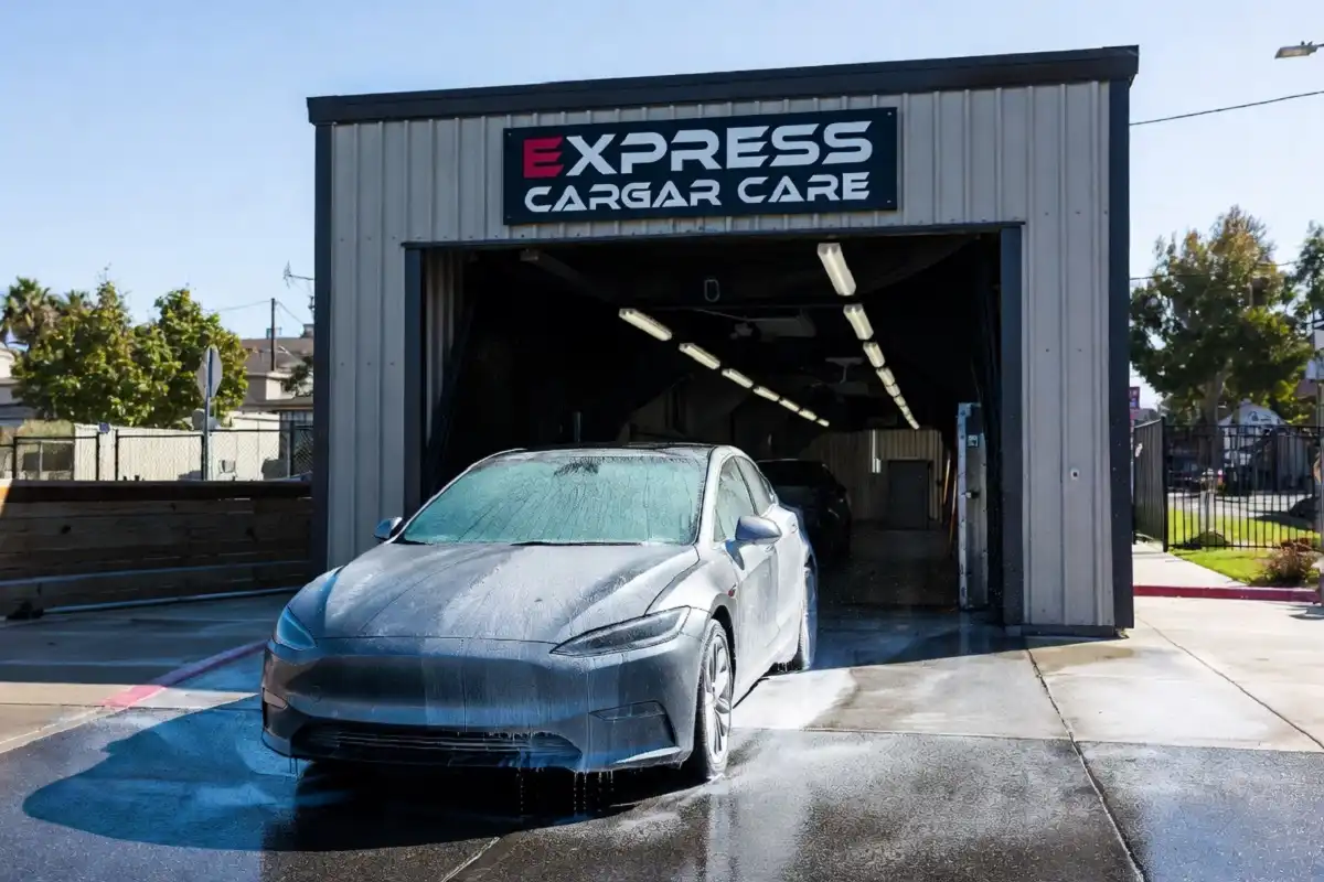 A clean, shiny car exiting an express car wash on a sunny day