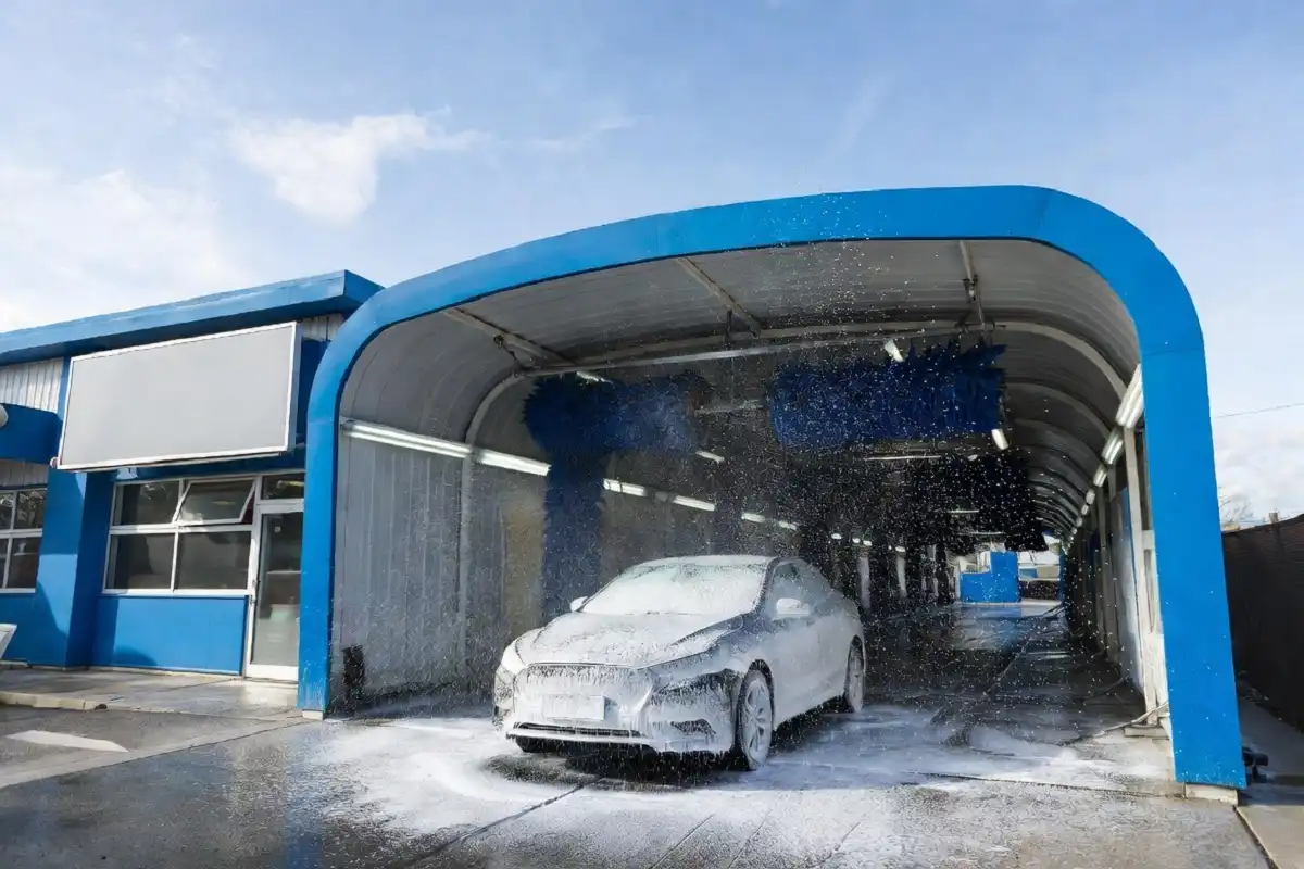 A car entering an express car wash tunnel with foam and spinning brushes