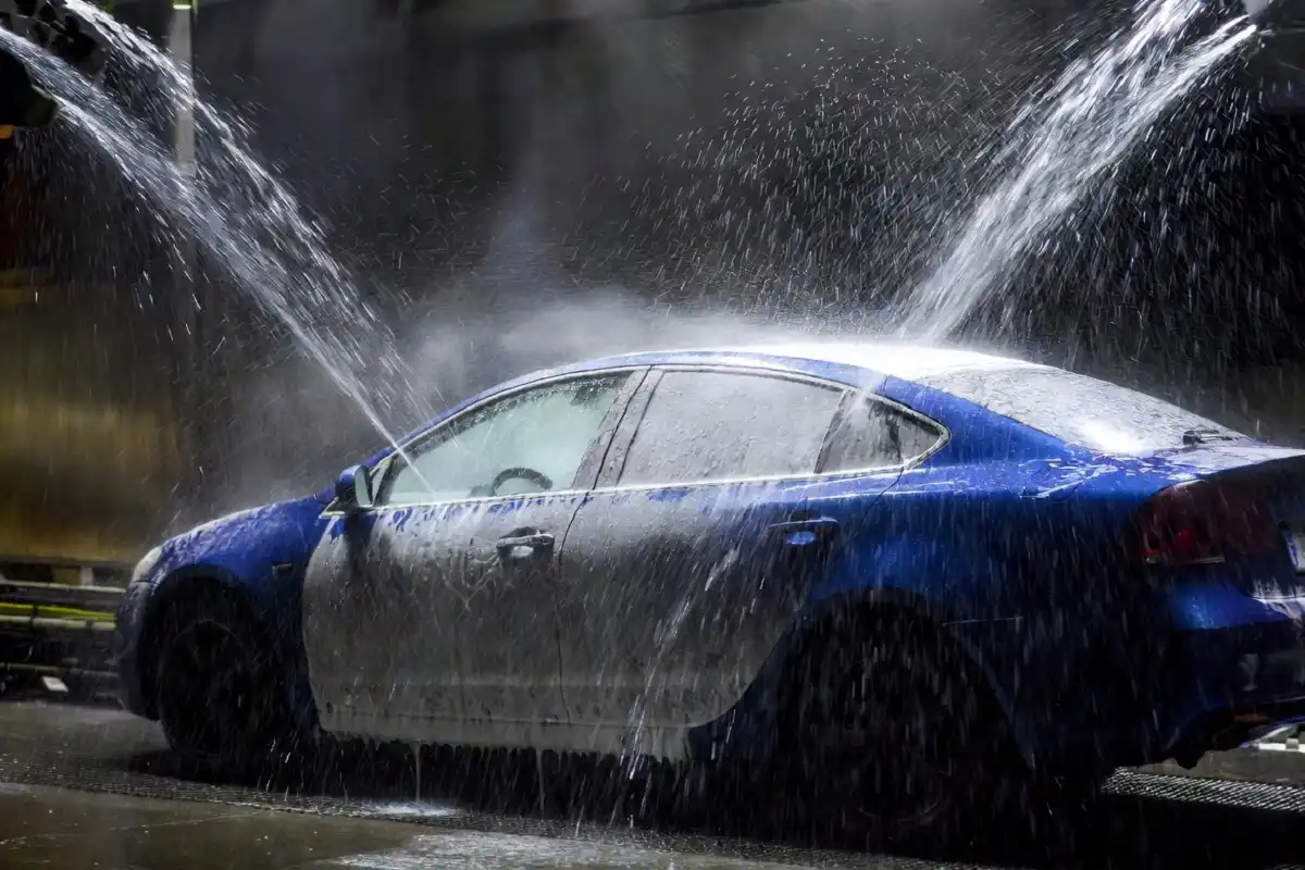 High-pressure water jets rinsing a car during an automatic gas station car wash cycle