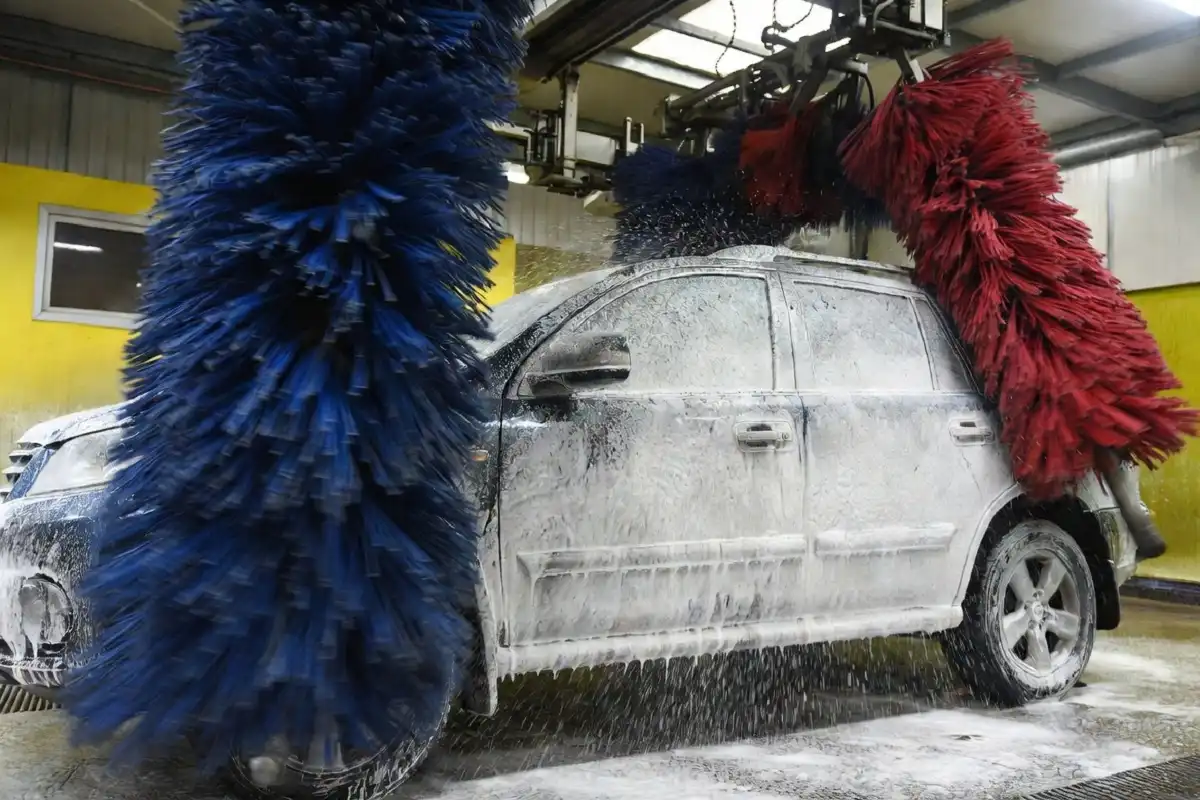 Soft cloth brushes wrapping around a car inside an automatic gas station car wash