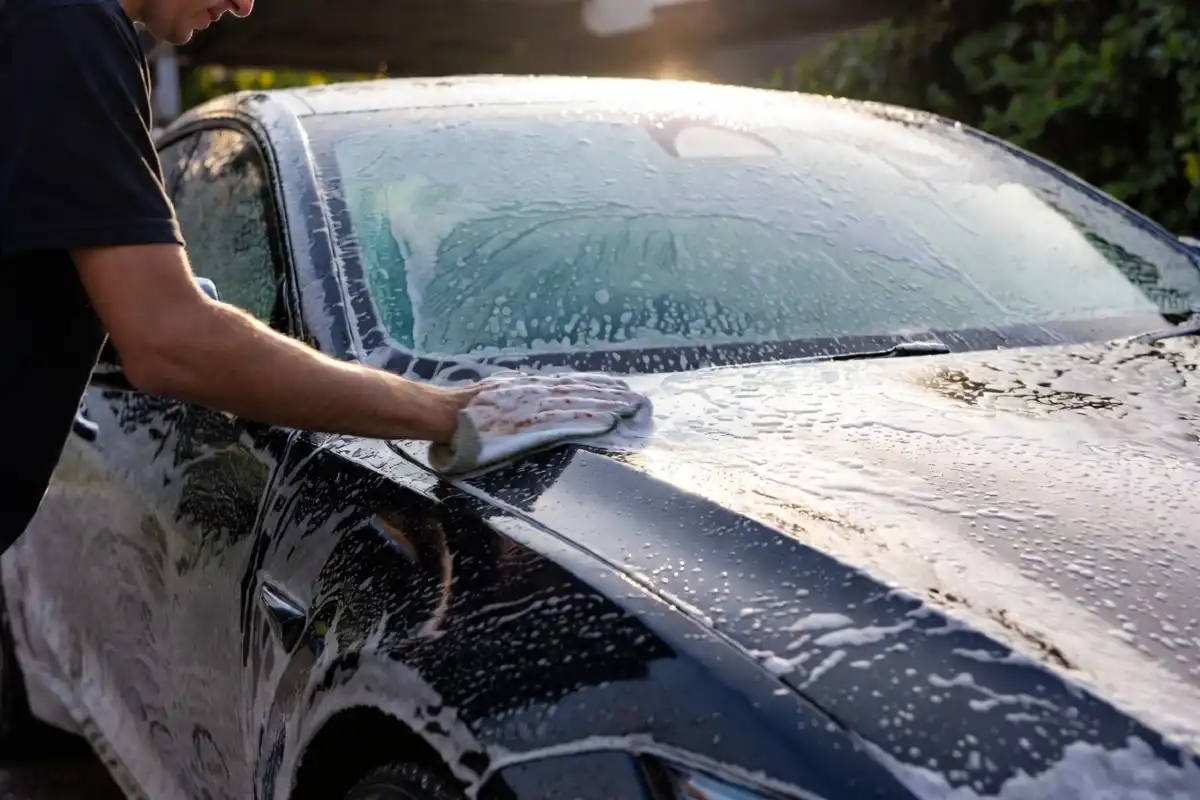 Professional hand washing a luxury black sedan