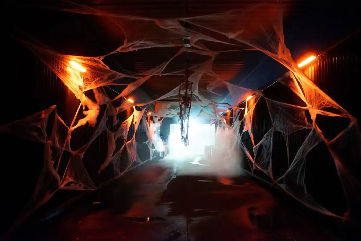 Haunted car wash tunnel decorated with Halloween lights, cobwebs, and skeletons at night