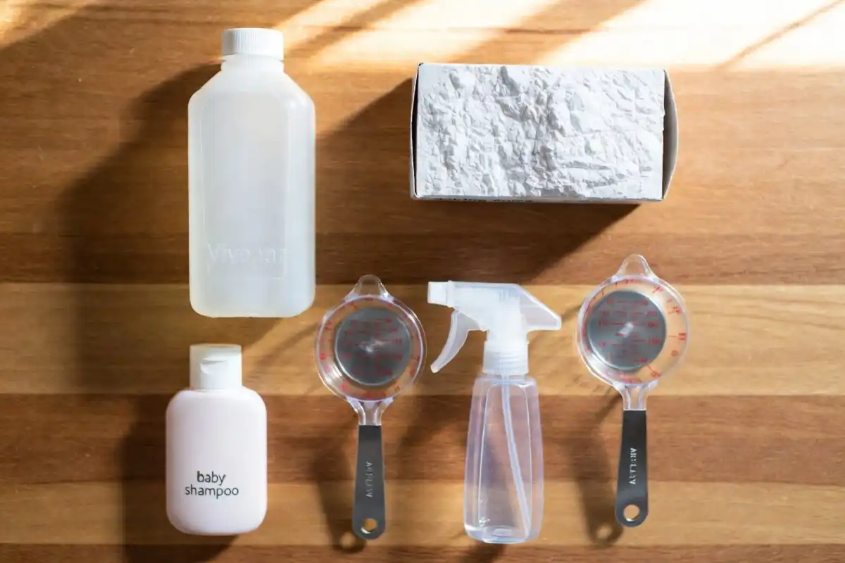 Homemade car wash soap ingredients including vinegar, baking soda, and dish soap on a wooden table