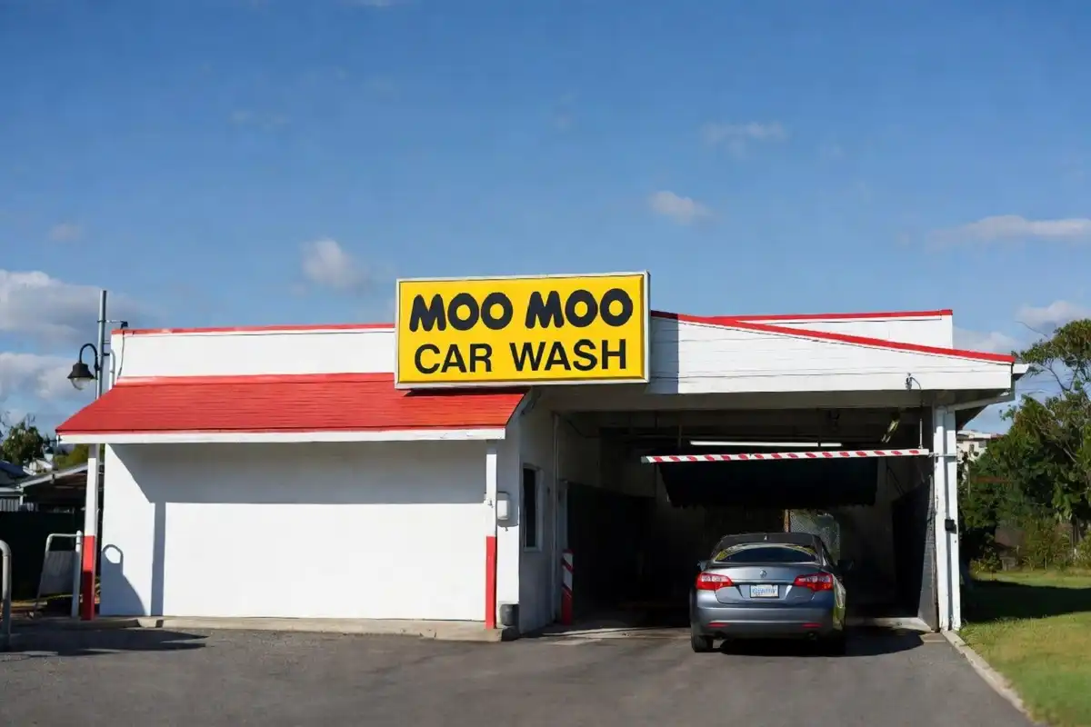 Exterior of a Moo Moo Car Wash location with signage and car entering the tunnel