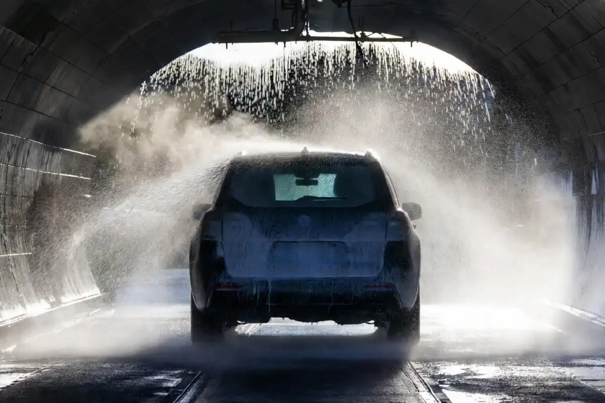 lack SUV being rinsed by high-pressure jets at the end of a Moo Moo Car Wash tunnel