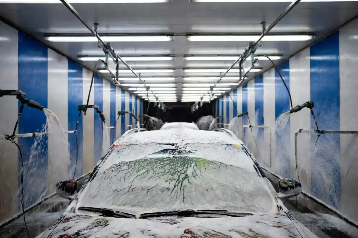 Foam applicators covering a white SUV inside a Moo Moo Car Wash tunnel