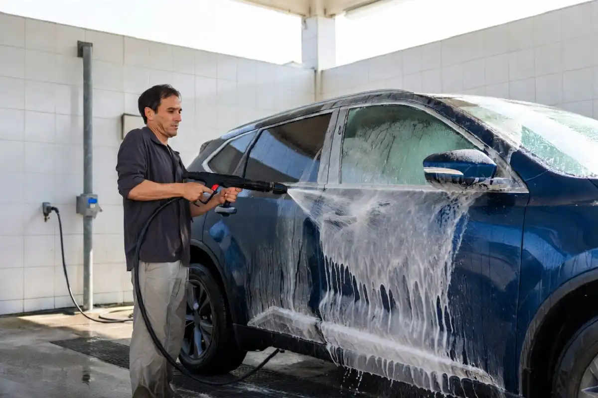 Man using high-pressure wand at a self wash car wash bay