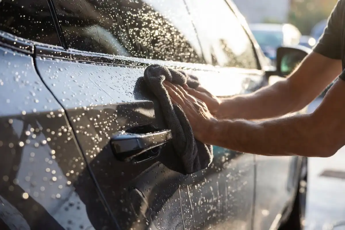 Person drying car with microfiber towel after self wash car wash