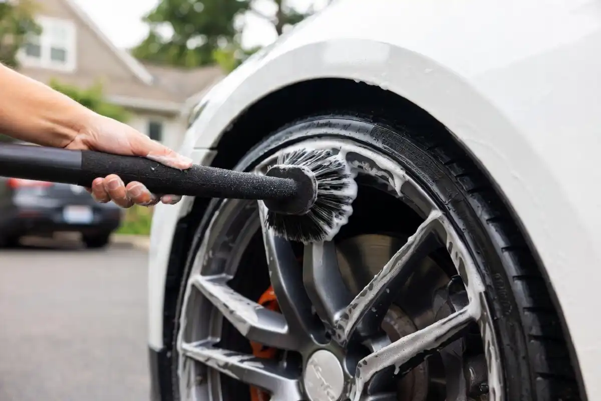 Using a wheel brush from a car cleaning kit to clean alloy rims