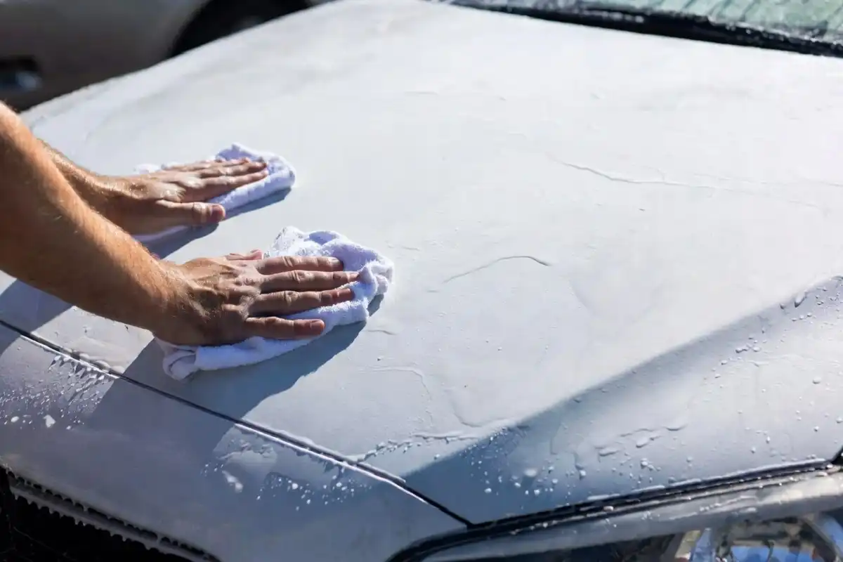 Microfiber towel being used to dry a white car after a white water car wash