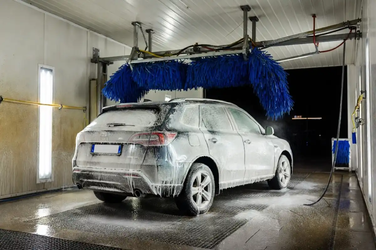 Silver SUV being cleaned with soft brushes inside a whitewater car wash