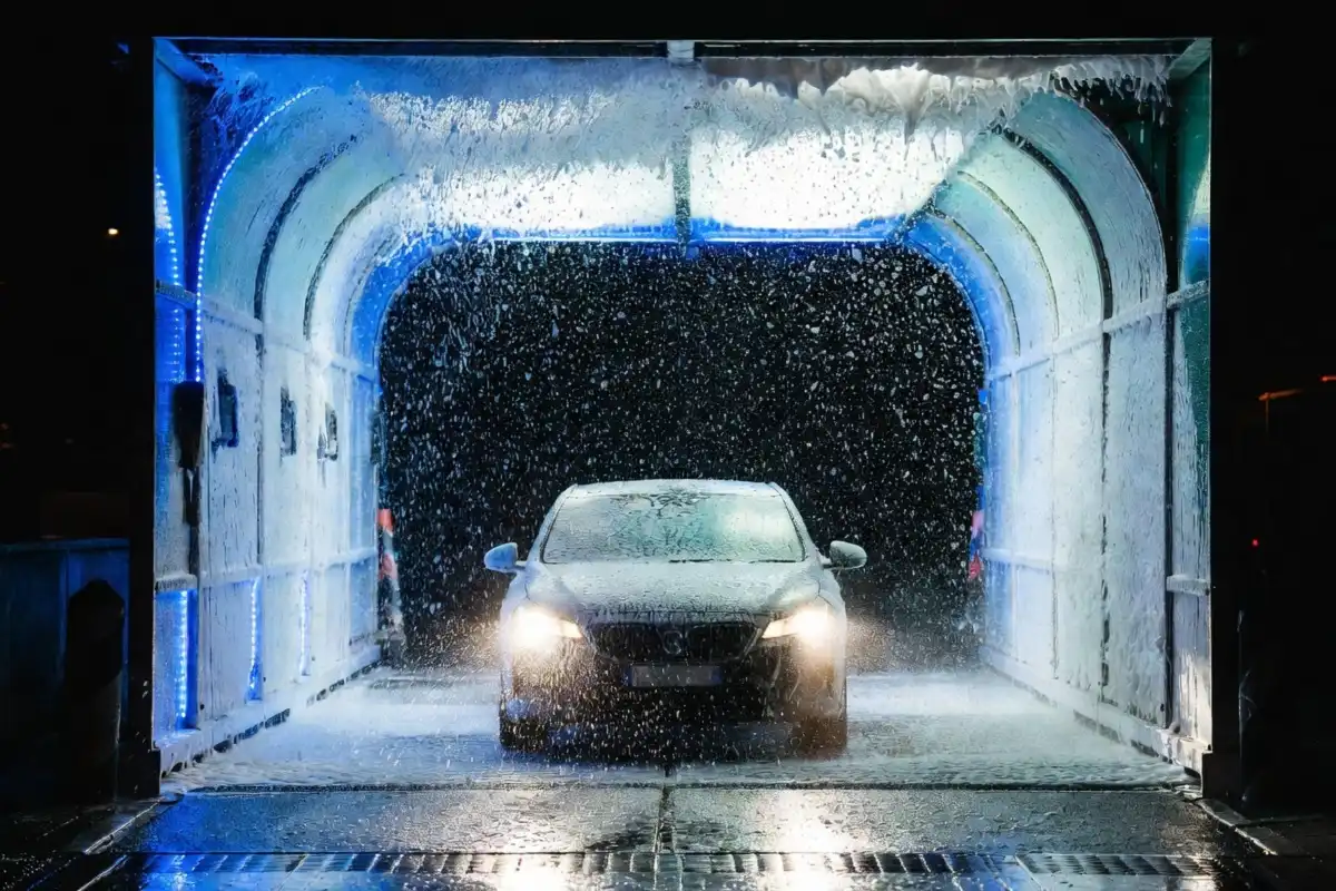 Car entering a whitewater car wash tunnel with foam and water jets